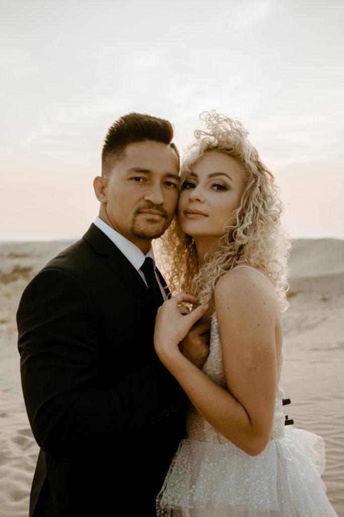 bride and groom holding each other in little Sahara desert