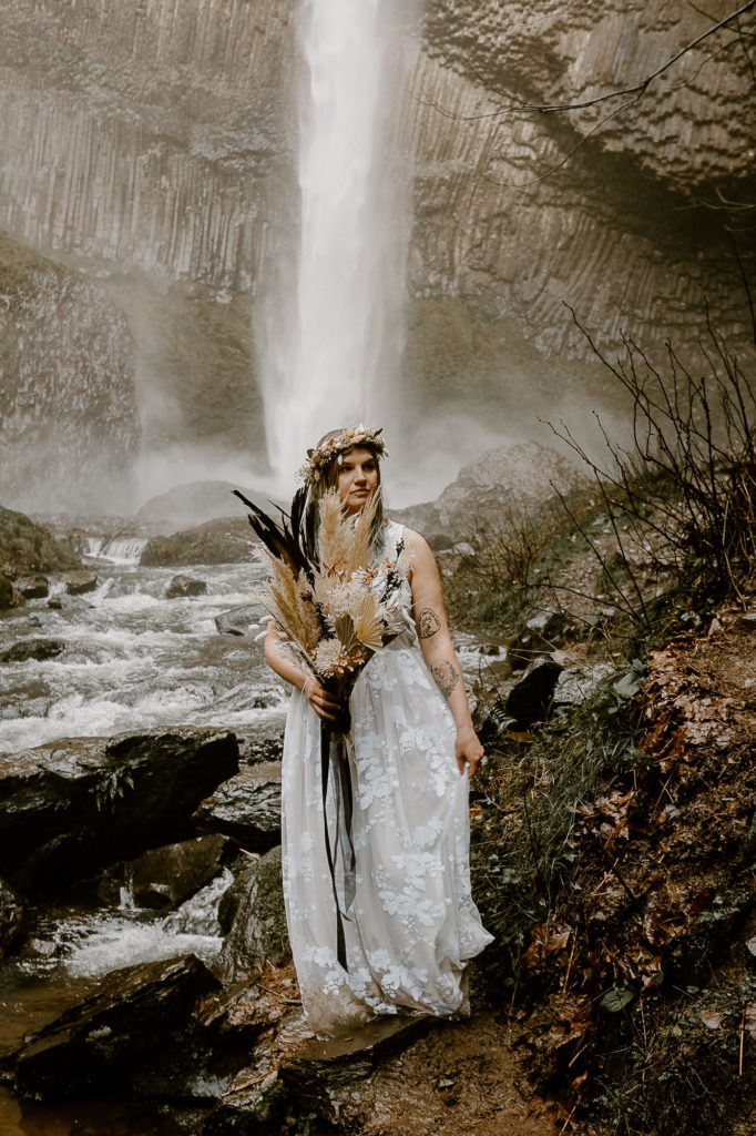 bride holding bouquet by waterfall
