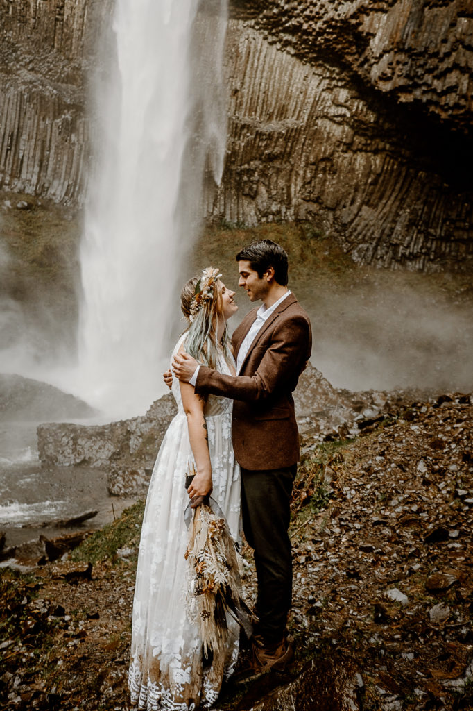 bride and groom looking at each other by a waterfall
