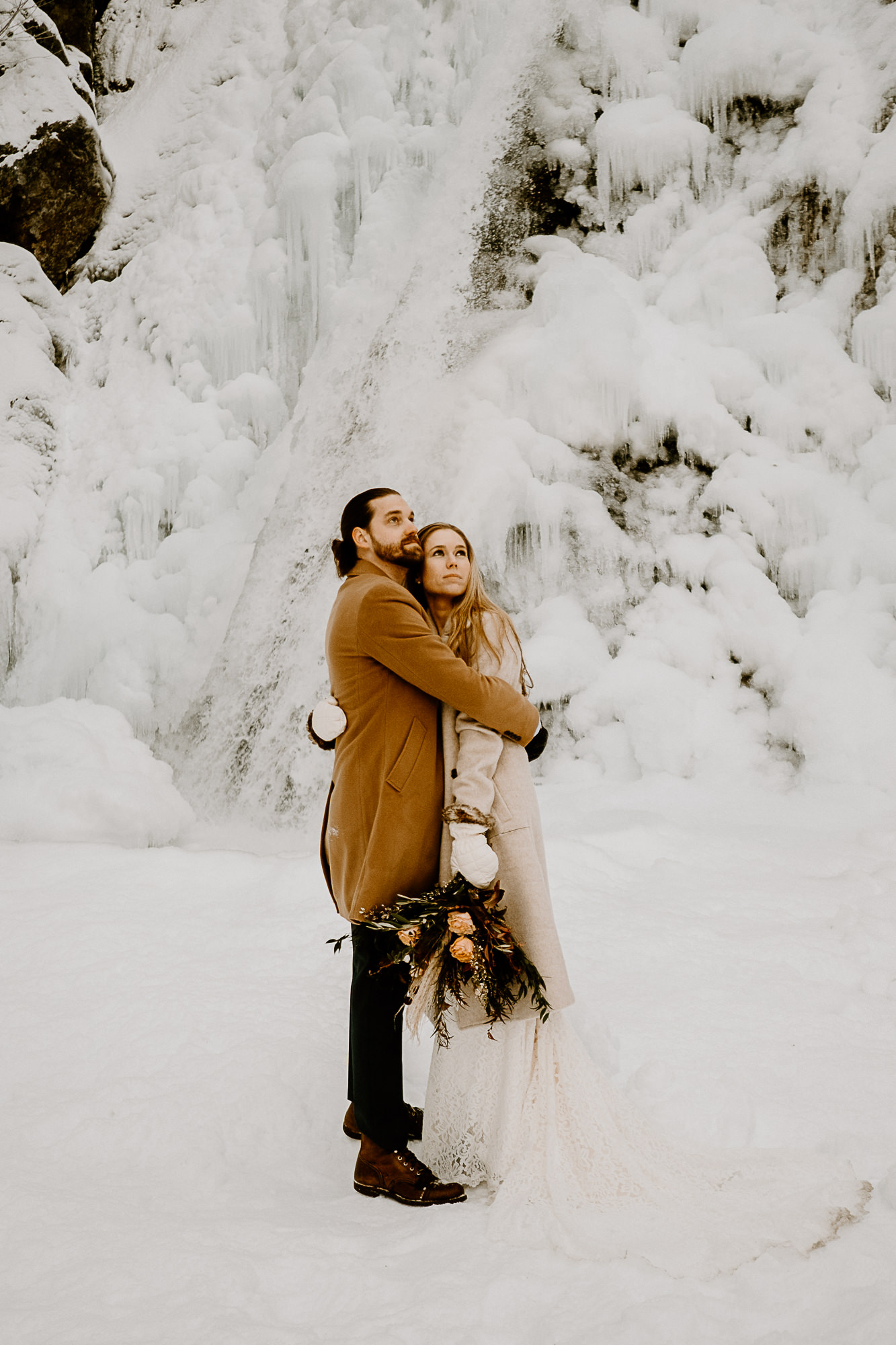 couple holding each other under a snowy waterfall
