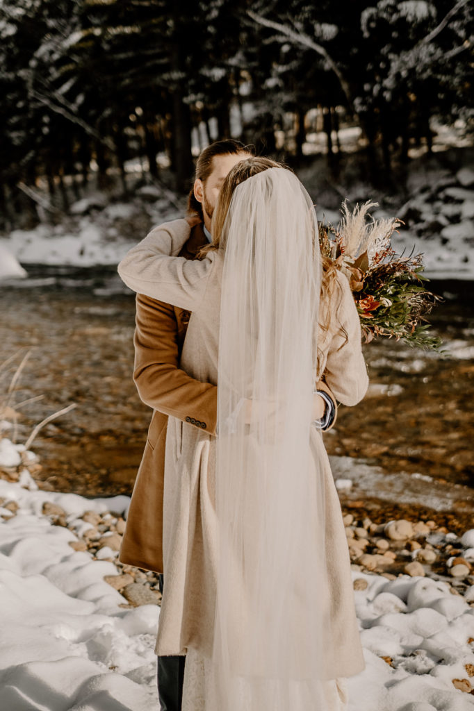 bride and groom kiss on a creek
