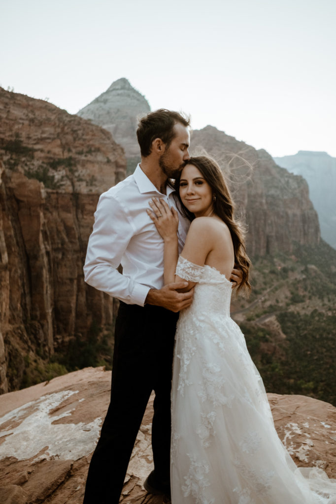bride and groom kissing over mountain