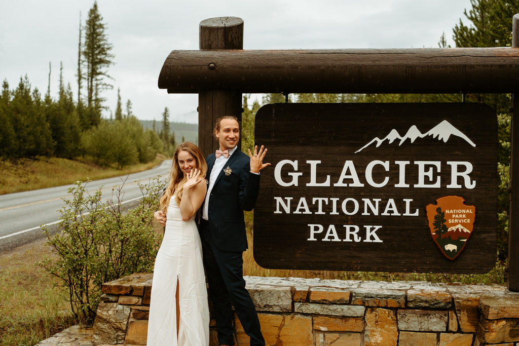 Couple posing with rings by National park sign
