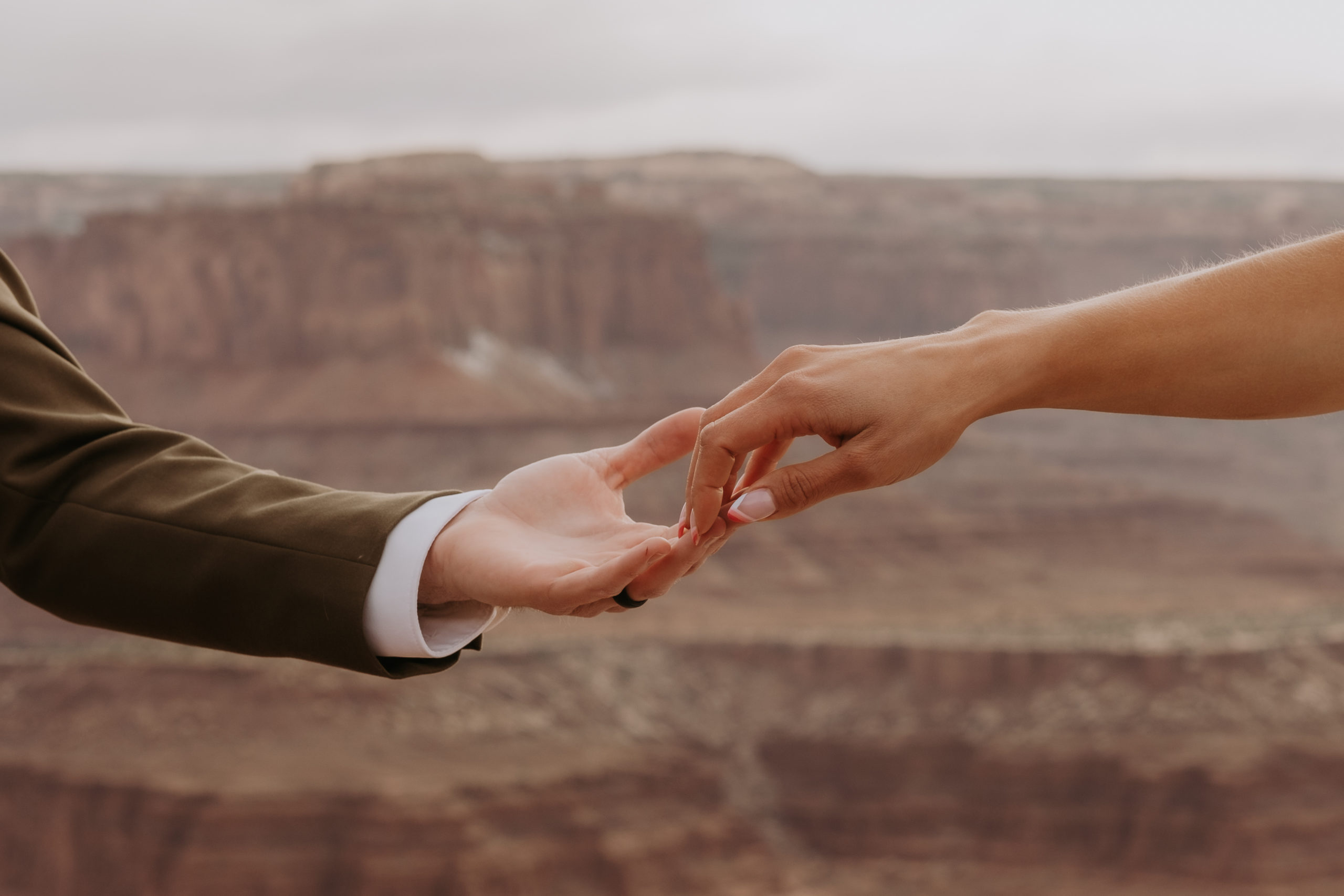 Two Individuals touching fingertips during thier dead horse state park elopement in Moab, utah