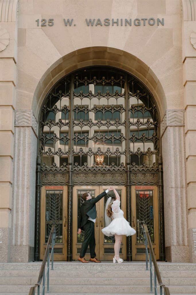Groom twirling bride in front of courthouse downtown Phoenix