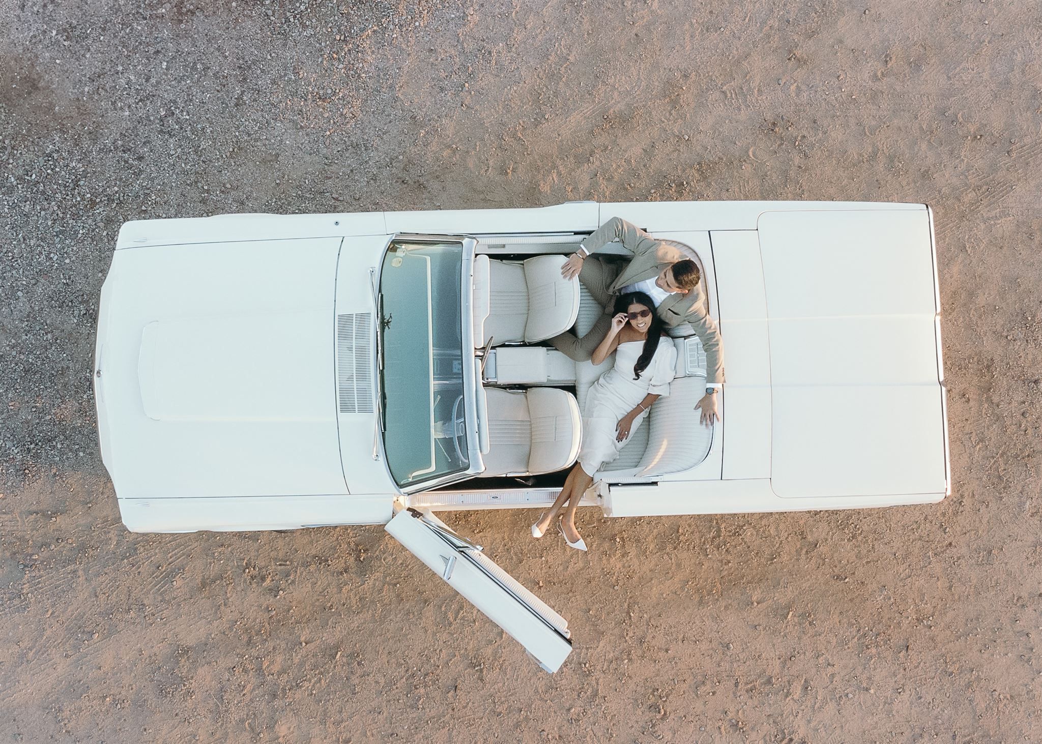 Man in women in vintage car sitting in the back smiling