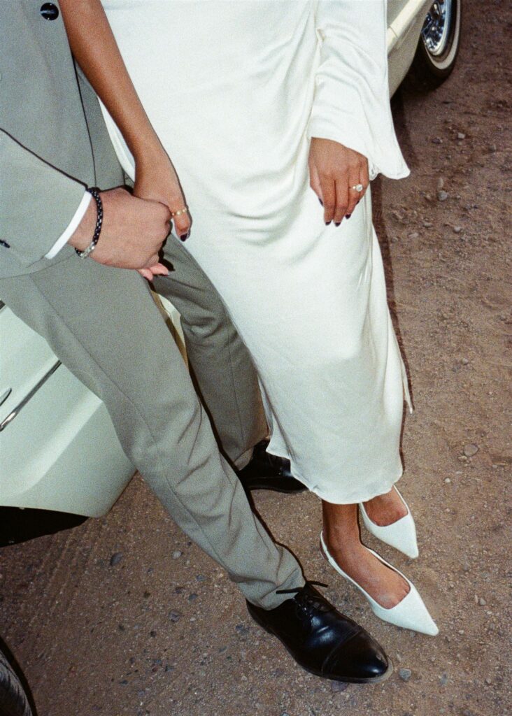 Man and woman holding hands in front of a vintage car