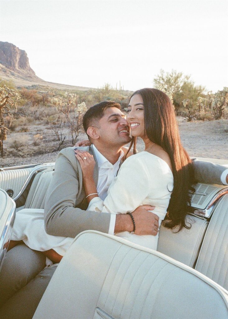 Man kissing womans cheek in a vintage car in the desert