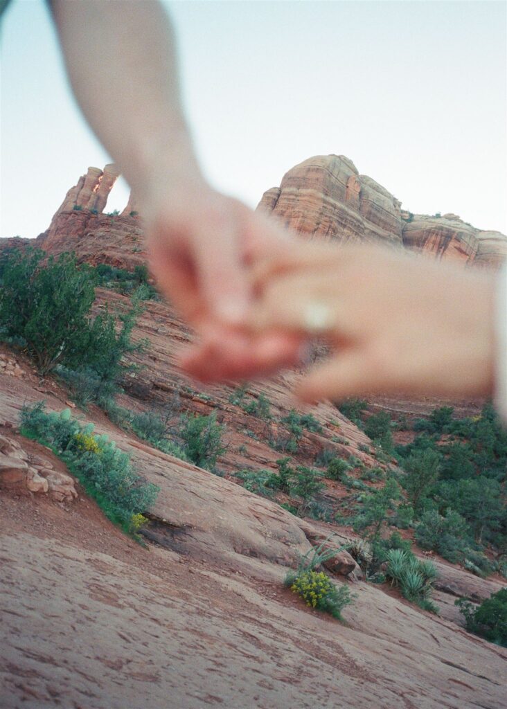 Cathedral Rock engagement photos in Sedona featuring a couple hiking and posing on red rock cliffs at sunset