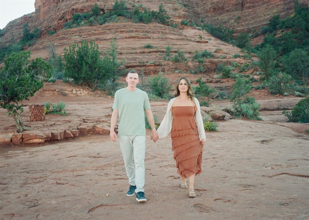 Cathedral Rock engagement photos in Sedona featuring a couple hiking and posing on red rock cliffs at sunset