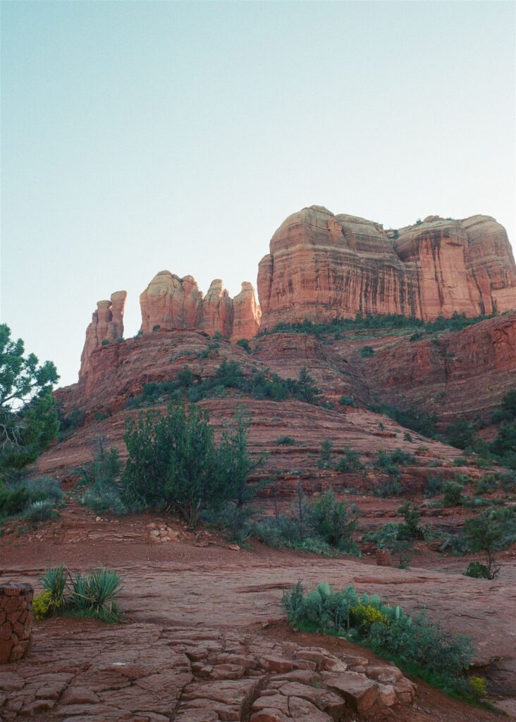 Cathedral Rock engagement photos in Sedona featuring a couple hiking and posing on red rock cliffs at sunset