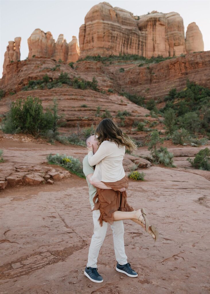 Cathedral Rock engagement photos in Sedona featuring a couple hiking and posing on red rock cliffs at sunset