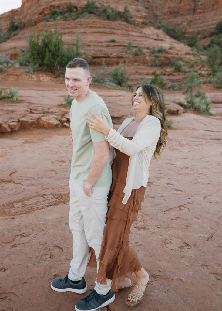 Cathedral Rock engagement photos in Sedona featuring a couple hiking and posing on red rock cliffs at sunset