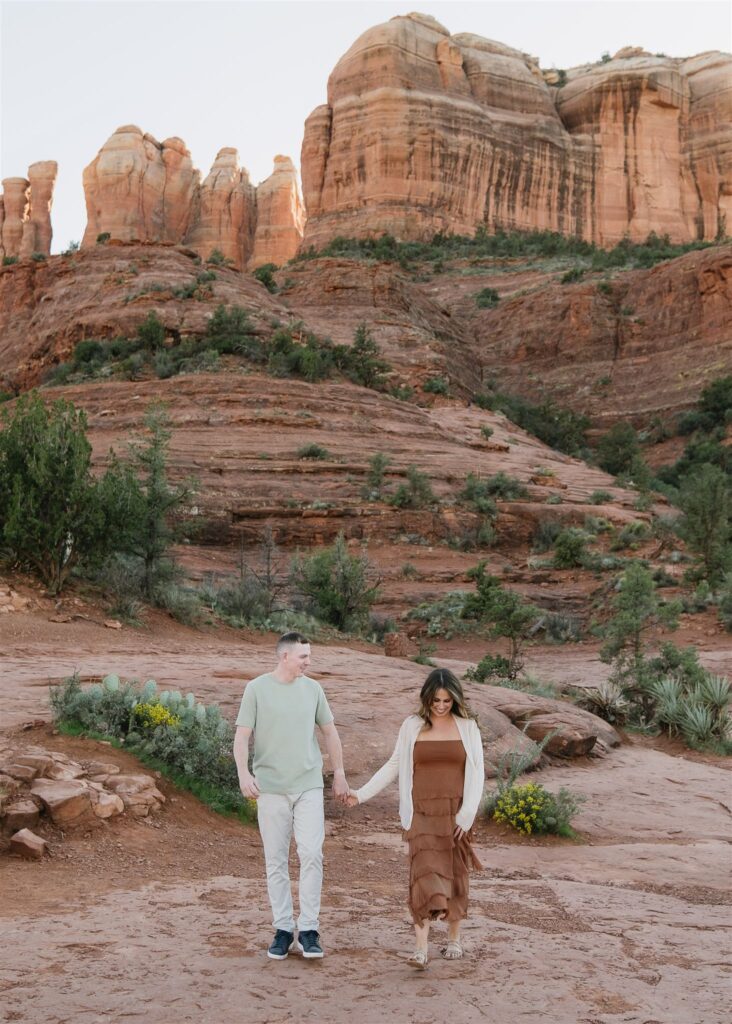 Cathedral Rock engagement photos in Sedona featuring a couple hiking and posing on red rock cliffs at sunset