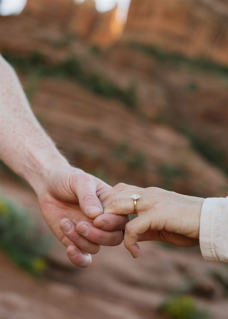 Cathedral Rock engagement photos in Sedona featuring a couple hiking and posing on red rock cliffs at sunset