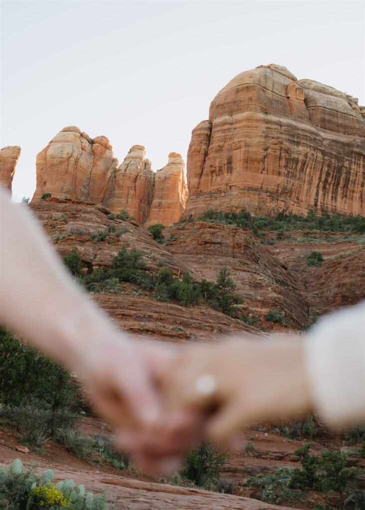 Cathedral Rock engagement photos in Sedona featuring a couple hiking and posing on red rock cliffs at sunset