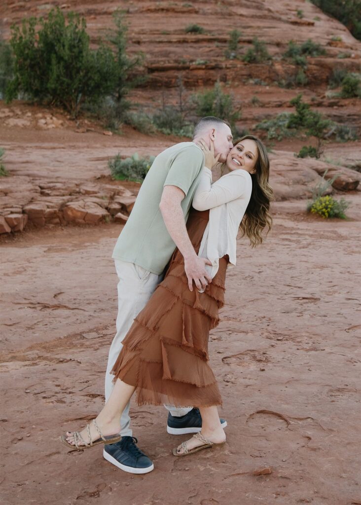 Cathedral Rock engagement photos in Sedona featuring a couple hiking and posing on red rock cliffs at sunset